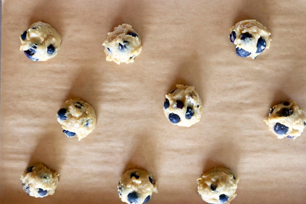 9 balls of blueberry-lemon cookie dough on a parchment-lined baking sheet.