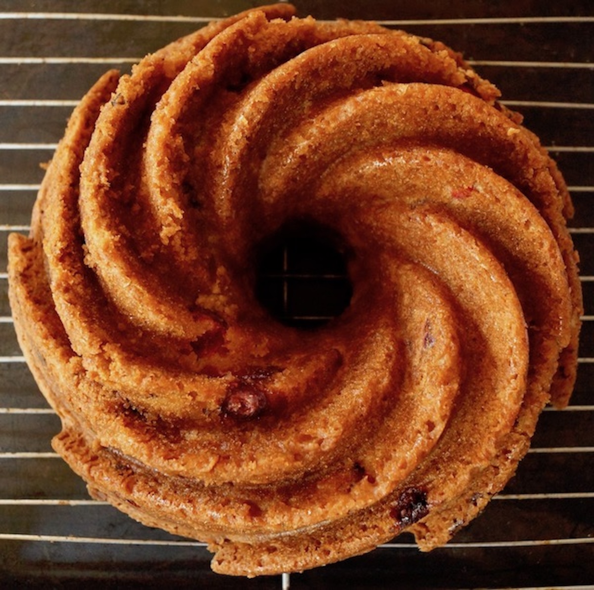 Golden baked bundt cake with a swirl pattern, on a wire rack.