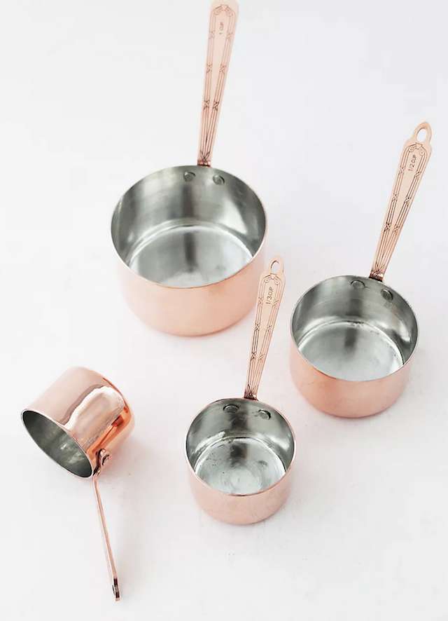 4 copper measuring cups on white background.