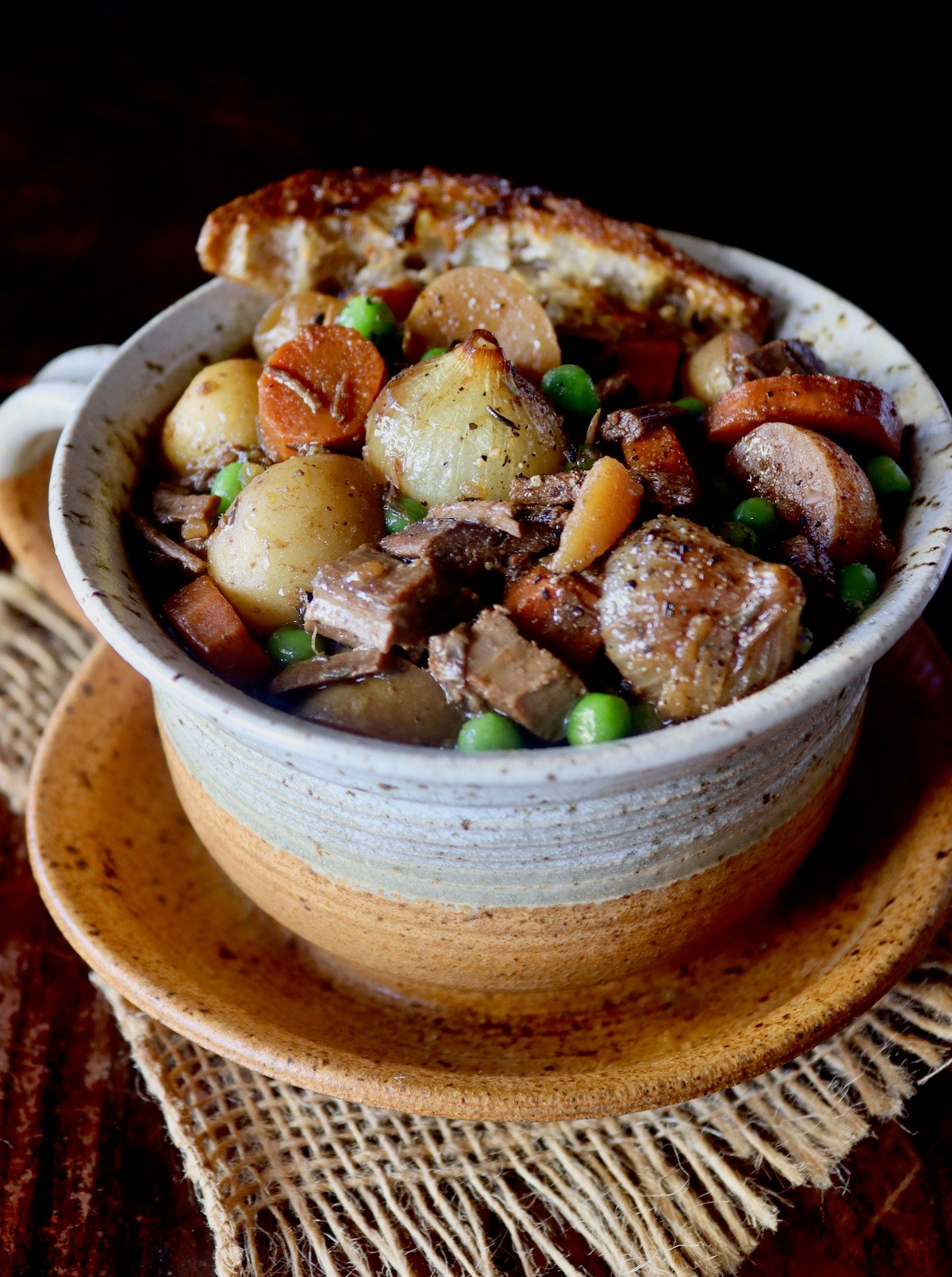 Close up of Braised Brisket stew in a giant bowl mug with bread on the edge.