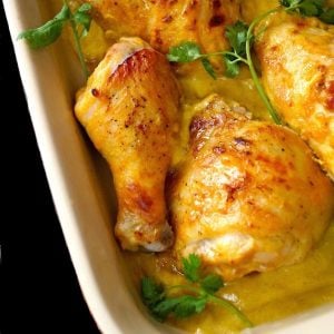 Chicken pieces on the bone baked in mango coconut sauce in a baking dish with fresh cilantro.