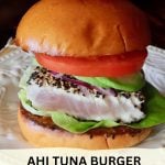 Sesame-Crusted Ahi Tuna Burger with tomato and avocado on a cream-colored plate - with text overlay of title.
