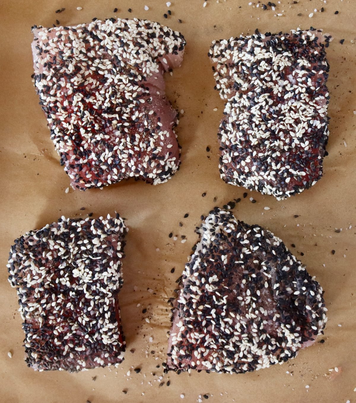 4 ahi tuna steaks with black and white sesame seeds on both sides.
