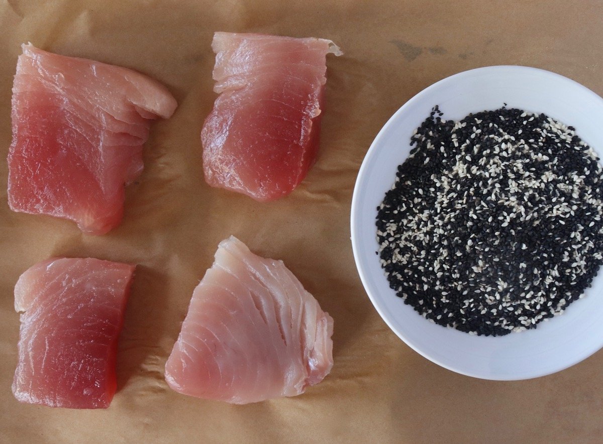 4 ahi tuna steaks with a shallow bowl of black andwhite sesame seeds.