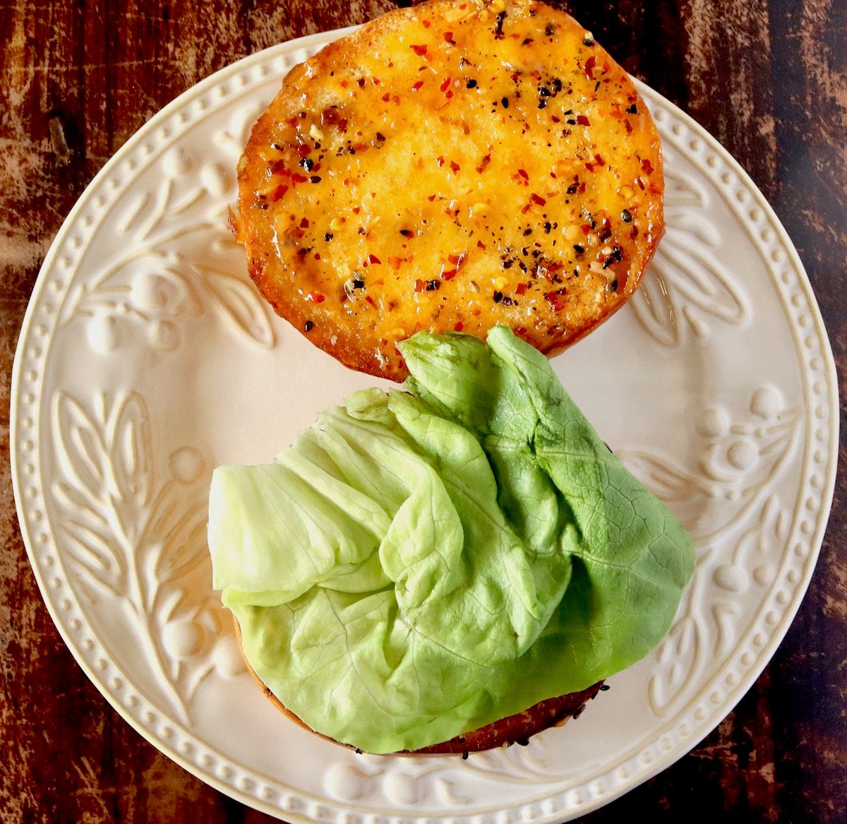 Hamburger bun with chili mayo spread over both halves, with butter lettuce on one of them.