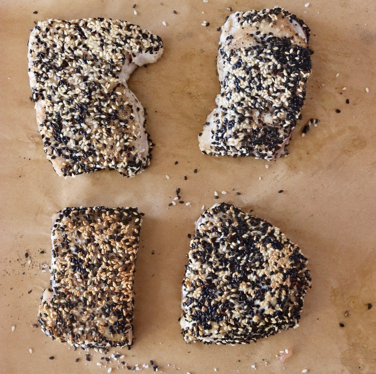 4 golden sesame-crusted ahi tuna burgers on parchment paper.