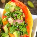 Papaya seeded and filled as a bowl with greens and avocado.