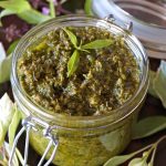 Open jar of lemon verbena pesto with small leaves on top.