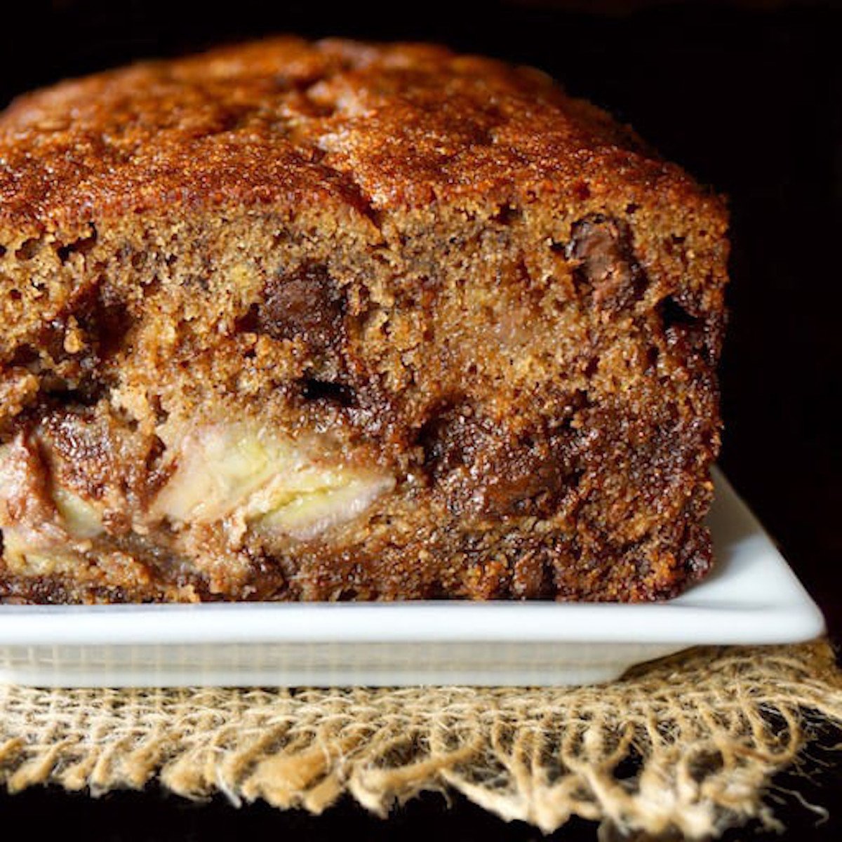 Cross section of banana chocolate chip cake on white square plate.