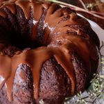 Close up of one whole gluten-free chocolate cake with chocolate glaze dripping down the sides.