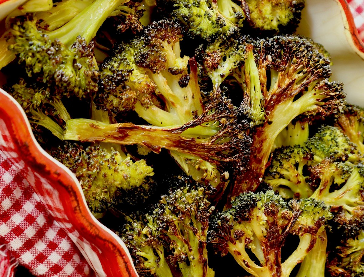 Red crimped-edge casserole dish filled with charred broccoli.