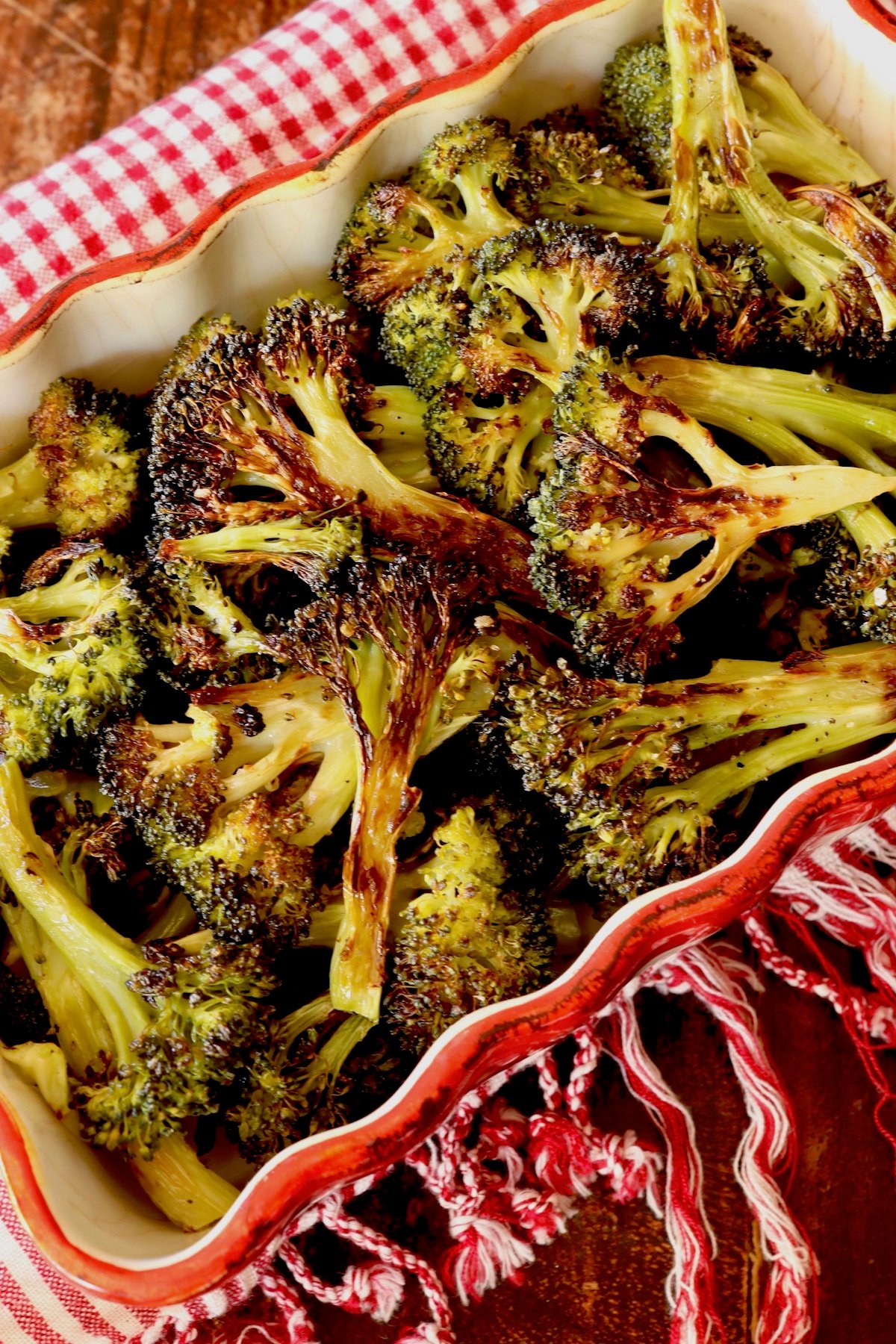 Red crimped-edge casserole dish filled with charred broccoli.