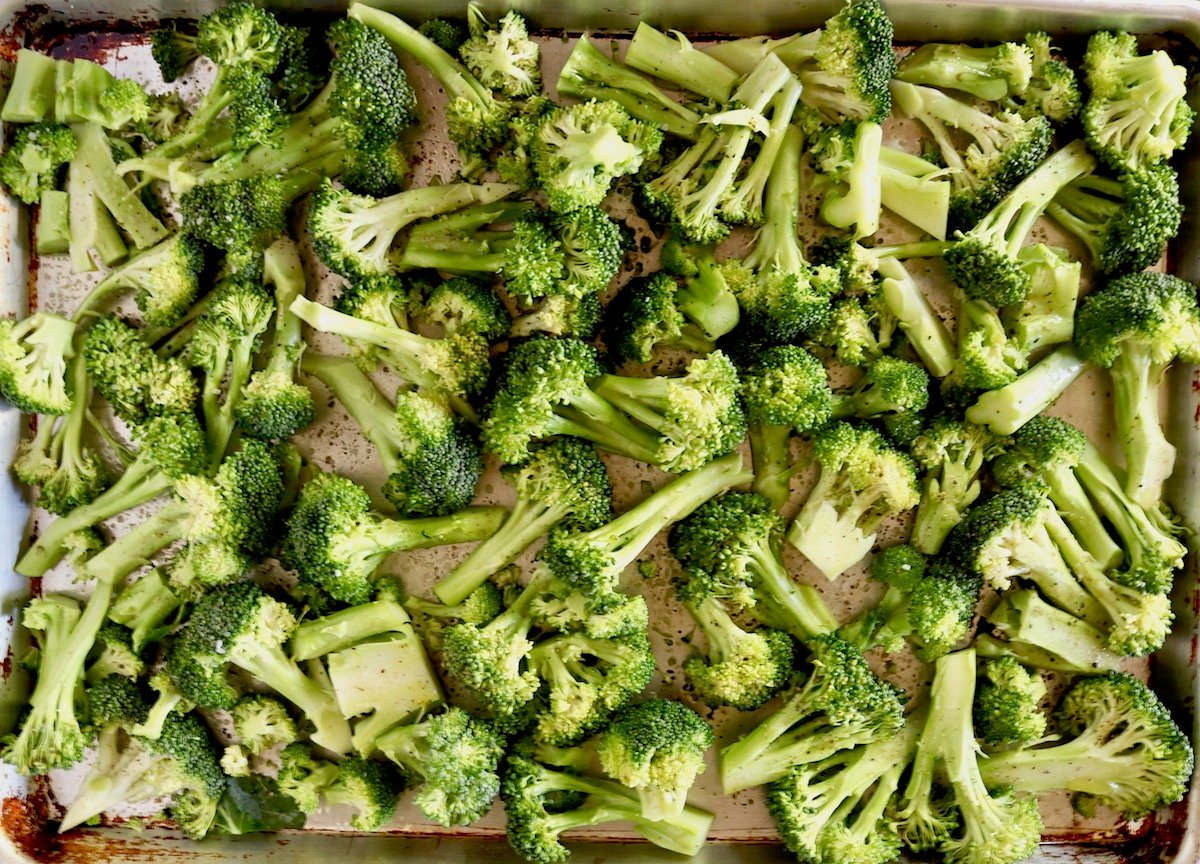 Sheet pan full of broccoli cut into bite-sized pieces.