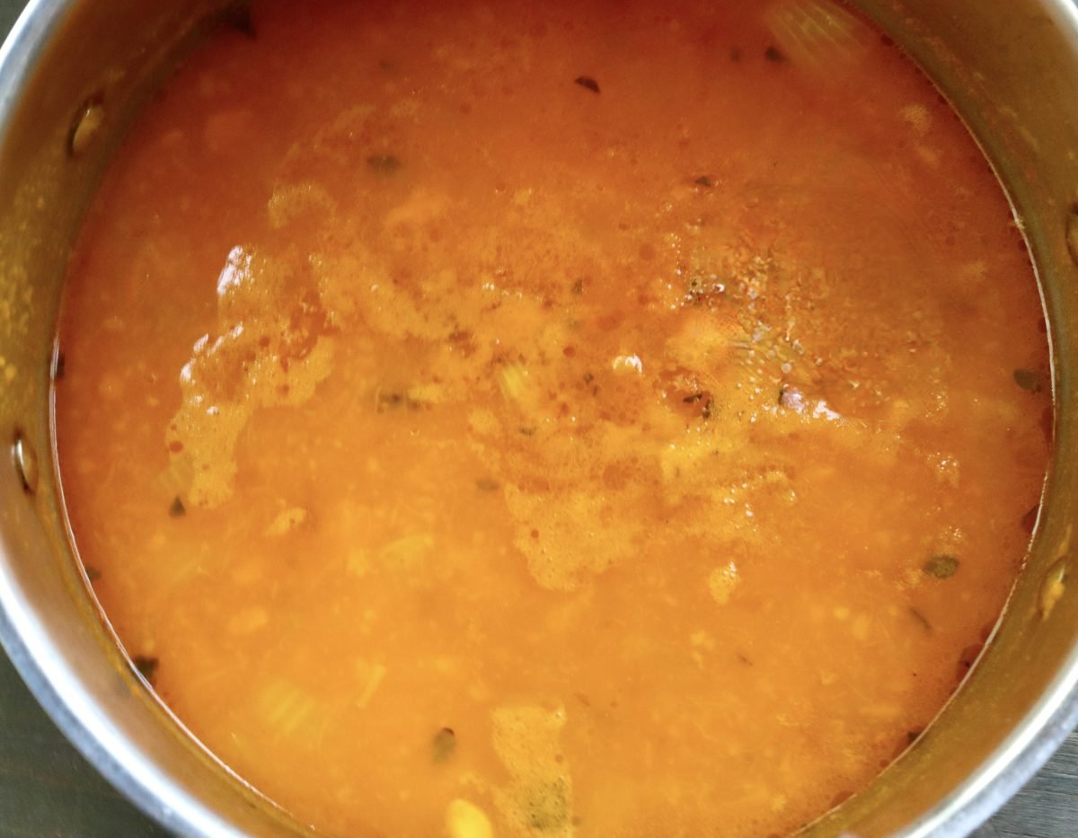 Red Kuri squash soup just before it's blended, in a large soup pot.