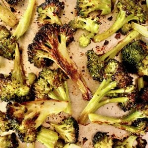 Sheet pan full of super charred broccoli cut into bite-sized pieces.