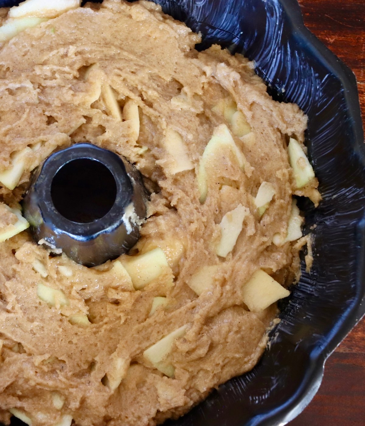 Chai Apple Cake batter pressed into buttered bundt pan.