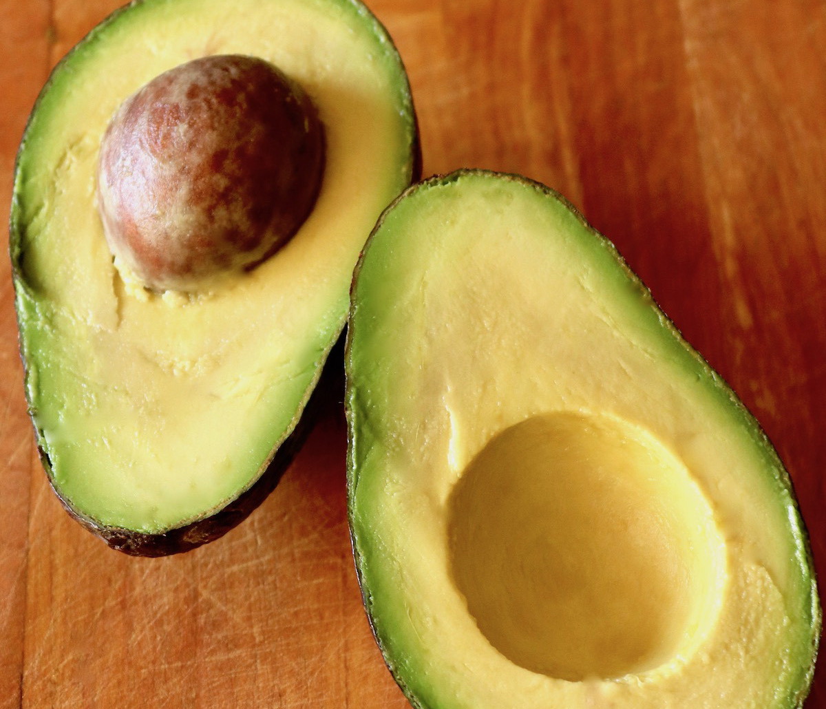 One avocado sliced in half with pit still intact.