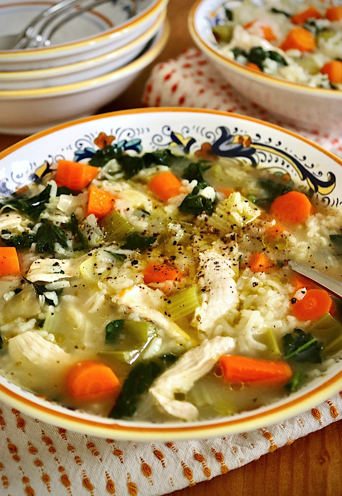 Italian yellow-edged bowl full with chicken and rice soup with carrot slices.