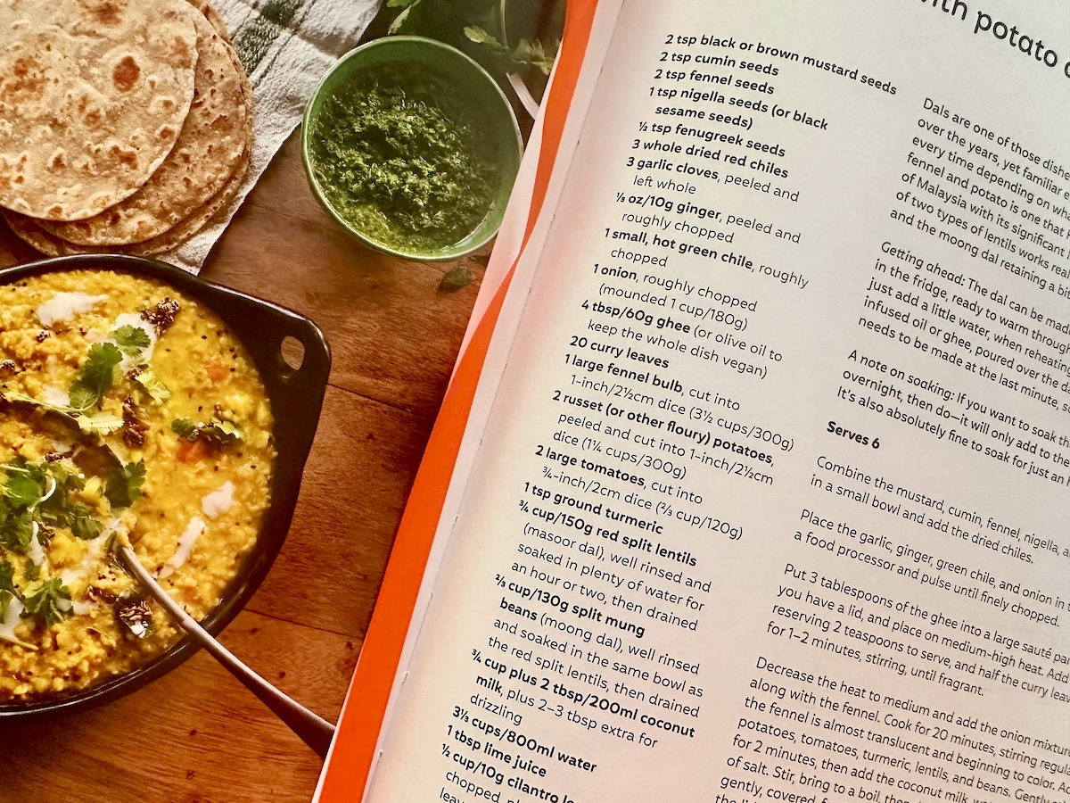 Open cookbook with a picture of Indian yellow dahl and green sauce.