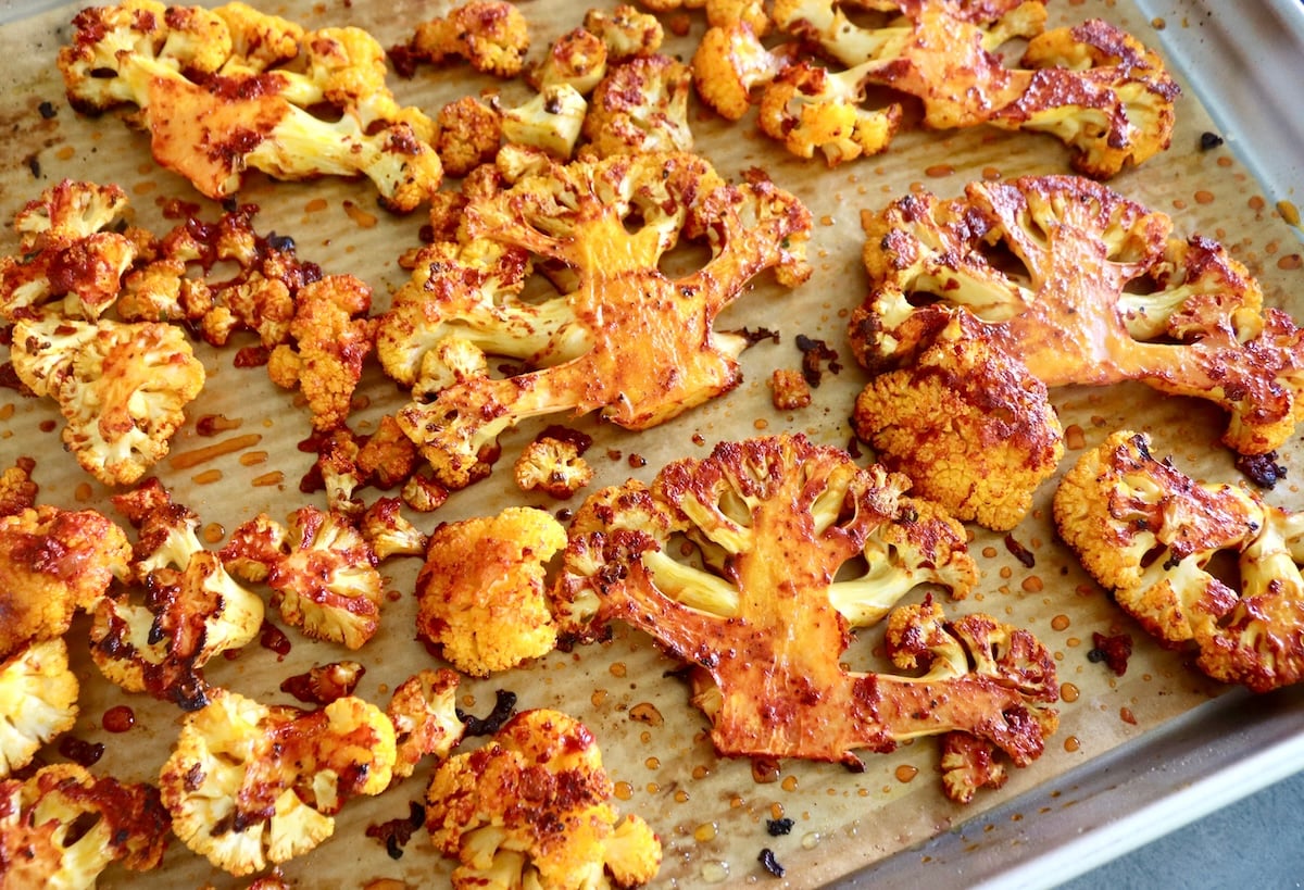 Roasted Achiote coated cauliflower slices on a baking sheet.
