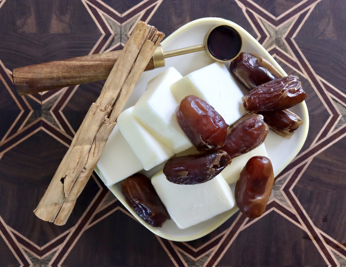 Large cinnamon stick with butter dish that's holding several pats of butter and serveral dates.