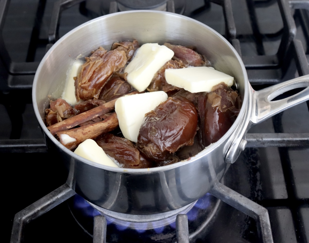 Small saucepan with dates, cinnamon stick and a few pats of butter.