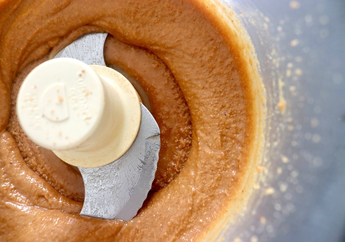 Close up of macadamia nut butter in a food processor bowl.
