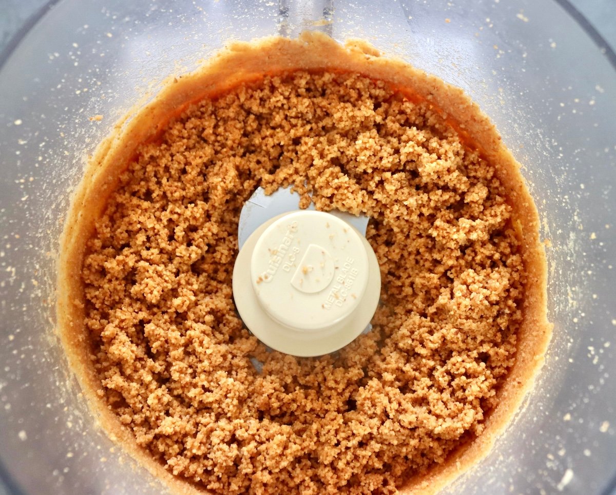 Super finely ground, paste-like macadamia nuts in a food processor bowl.