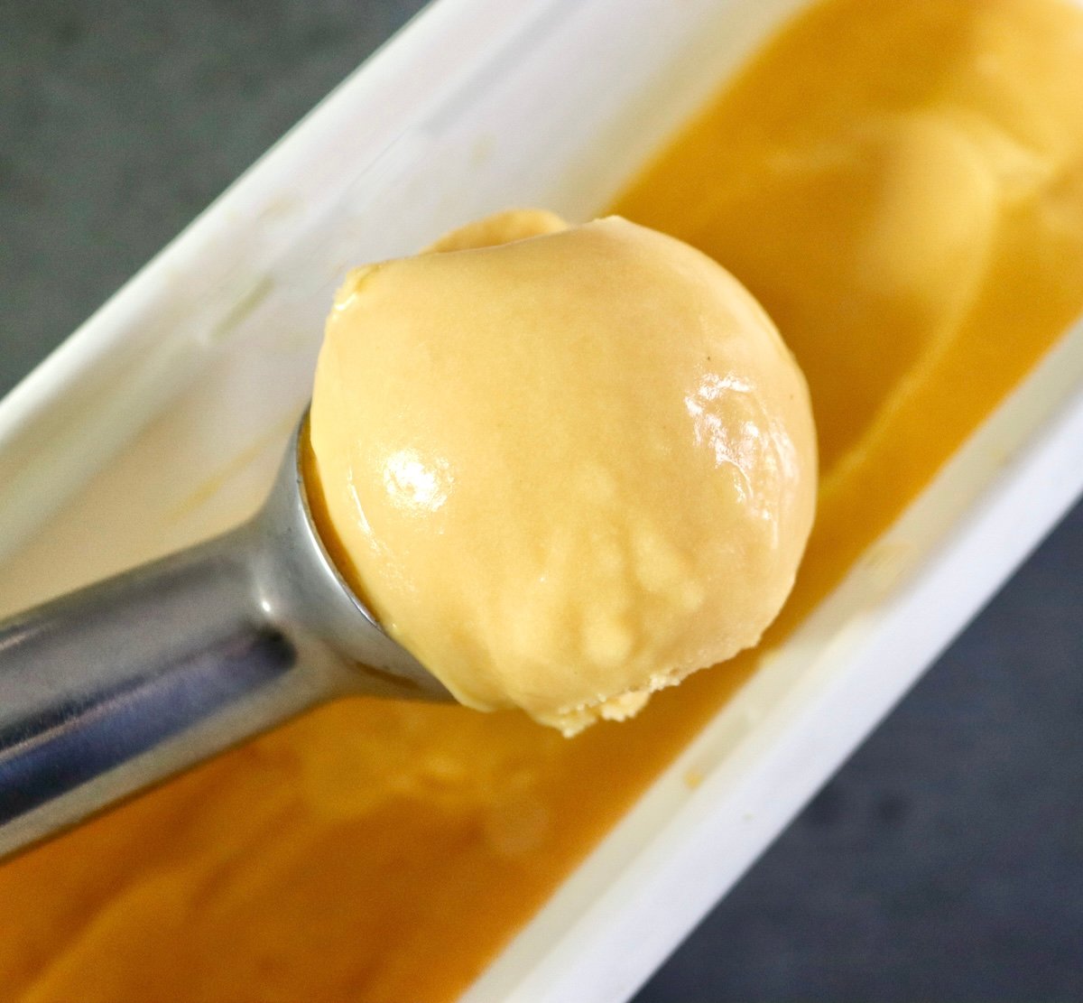 One scoop of passion fruit ice cream in an ice cream scoop.