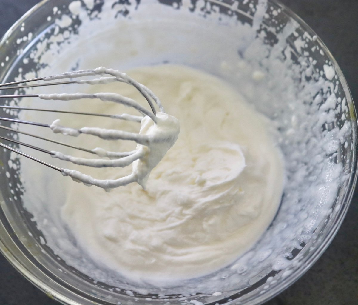 Bowl of whipped cream with a whisk.