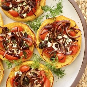 One side of a round platter with 4 spaghetti squash tiny pizzas with fresh dill in between.