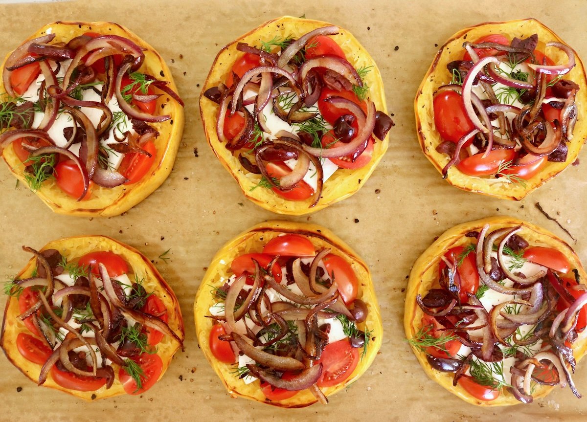 Spaghetti-Squash-Rings-with-Feta-and-Olives Several cooked spaghetti squash rings with feta, red onion and tomatoes on top.