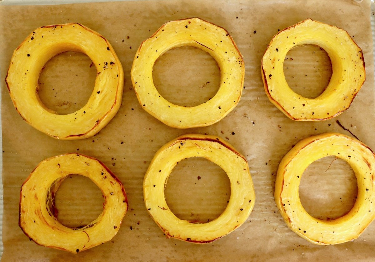 Spaghetti-Squash-Rings-with-Feta-and-Olives 6 roasted spaghetti squash rings on a parchment-lined baking sheet pan.