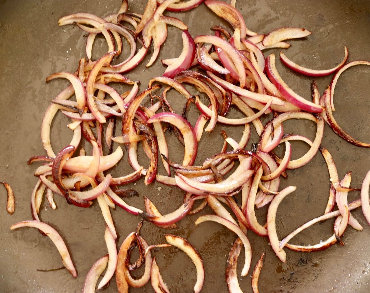 Spaghetti-Squash-Rings-with-Feta-and-Olives Sautรฉed red onion slices in a skillet.