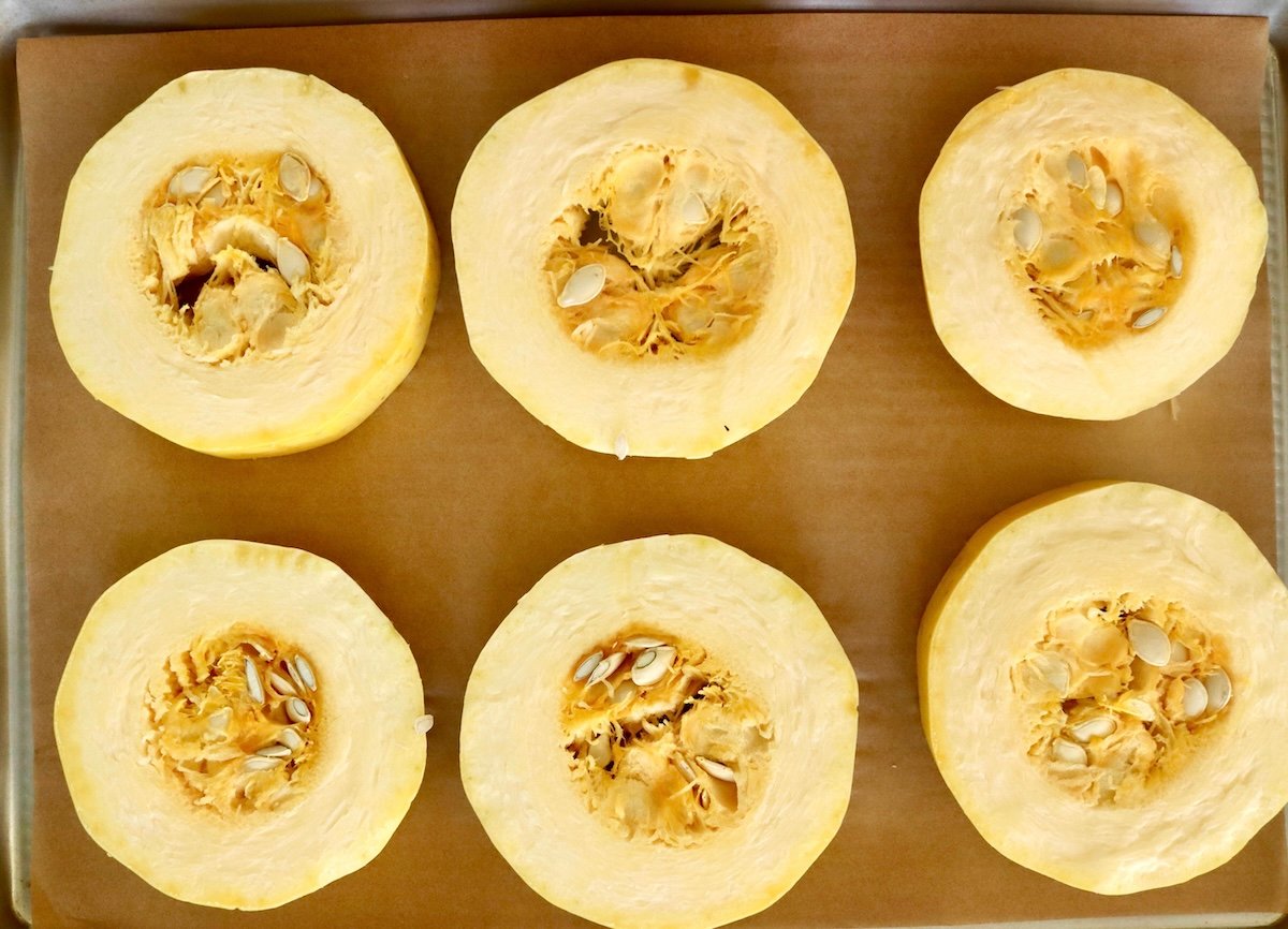 Spaghetti-Squash-Rings-with-Feta-and-Olives 6 raw spaghetti squash rounds on a parchment-lined sheet pan.