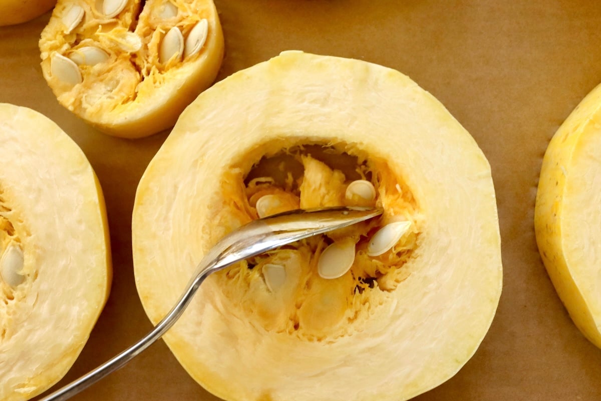 Spaghetti-Squash-Rings-with-Feta-and-Olives Spaghetti squash ring with a spoon removing the seeds from the center.