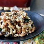 Black plate with a serving of black-eyed pea casserole, with a red baking pan behind it.