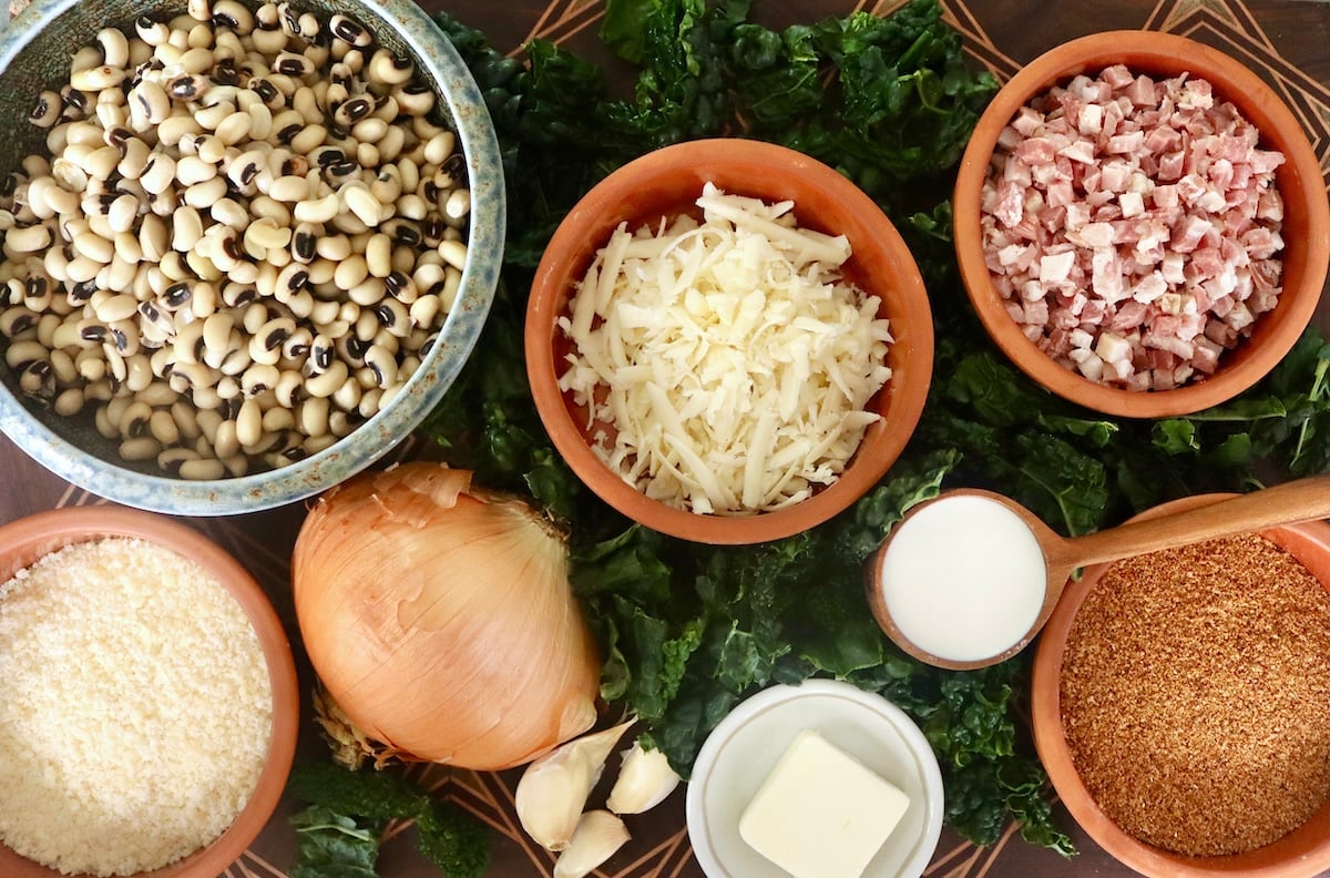 Black-Eyed Pea Casserole Ingredients for black-eyed pea casserole including the peas, cheese, onion, garlic, butter, cream, pancetta, breadcrumbs and kale.