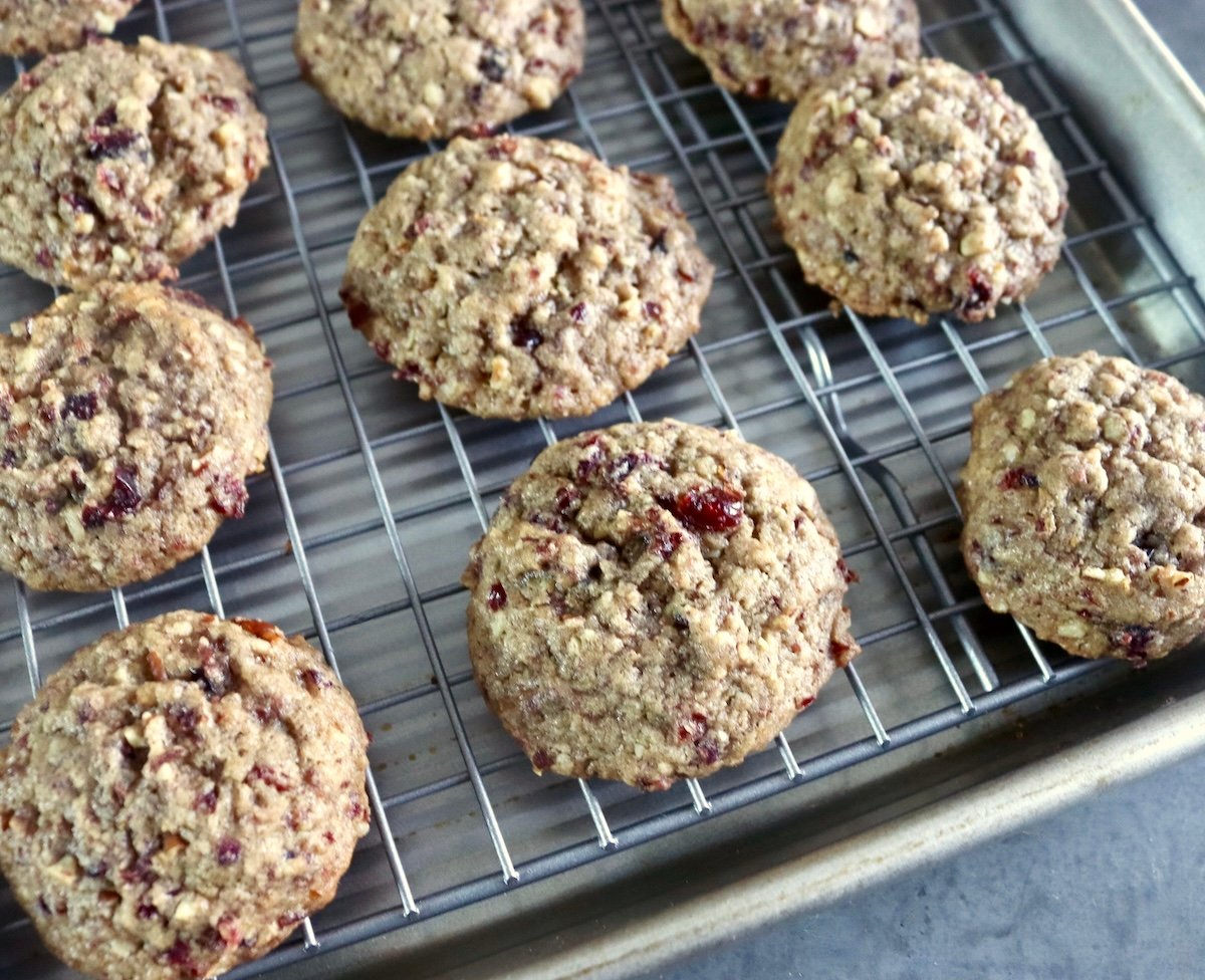 Several baked pecan cranberry cookies on a baking rack.