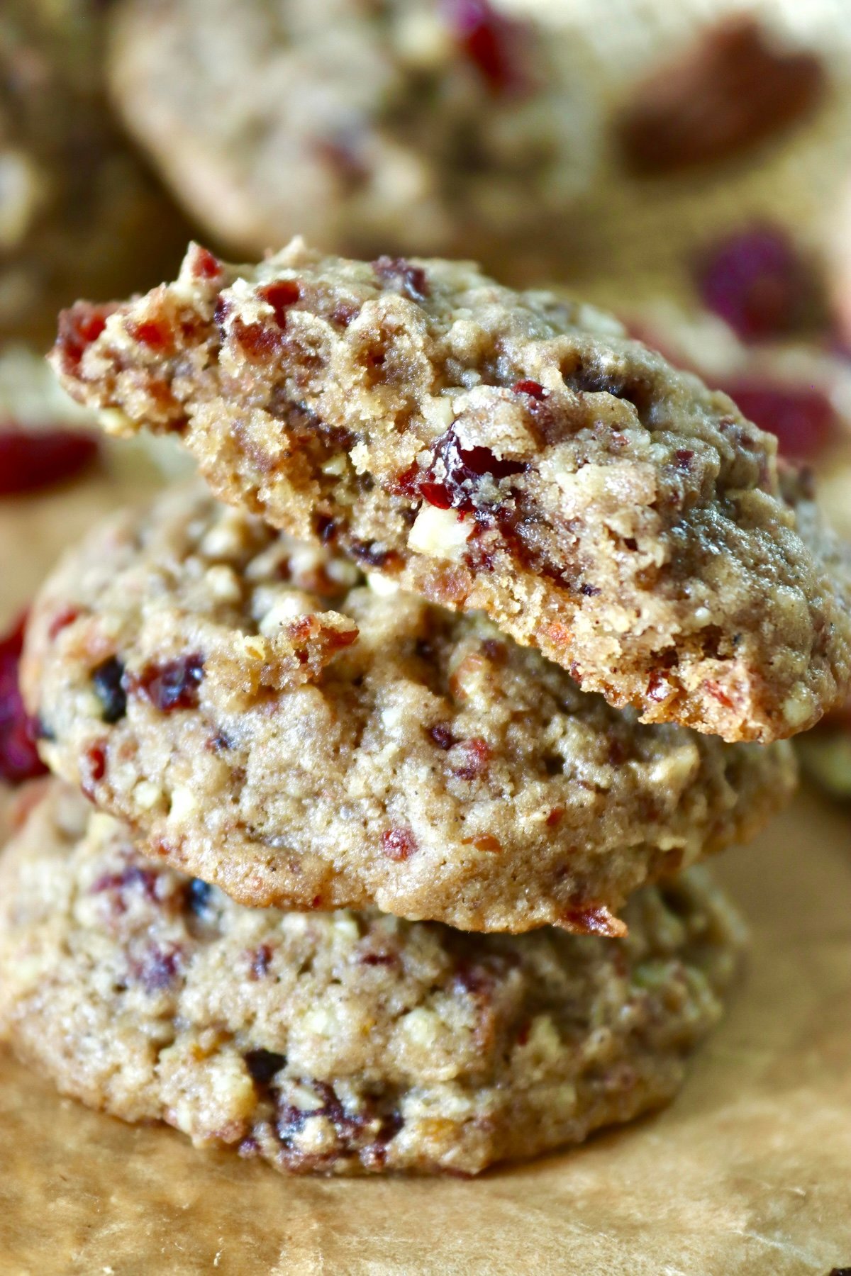 Three stacked pecan cranberry cookies with a bite taken out of one.
