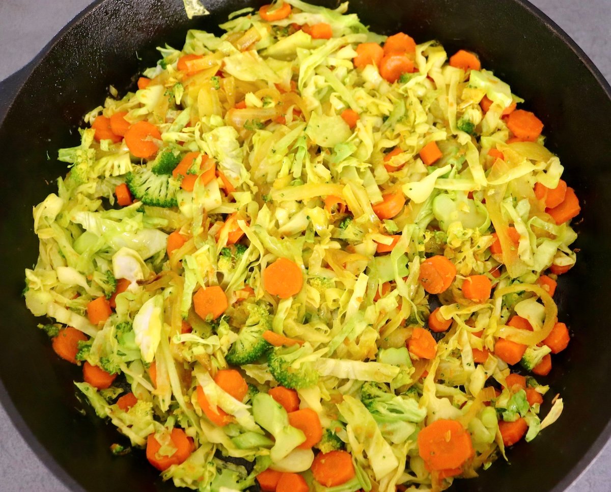 Baked-Red-Snapper-Recipe Large cast iron skillet filled with sauteed cabbage, broccoli, onion and carrots.