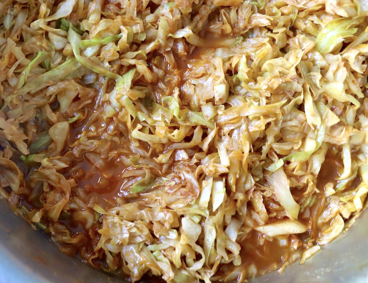 Sautéed and wilted cabbage with tomato sauce in a sauté pan.