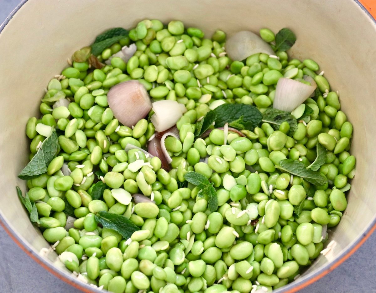 Edamame-Soup-Recipe Dutch oven full of edamame, shallots, and mint leaves.
