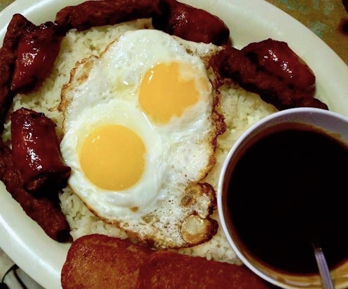 Oval plate with sausages, rice, brown gravy and 2 sunny-side up eggs.
