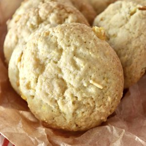 Close up of crispy, perfectly round, cornbread cookies, on parchment paper on a red and white cloth.