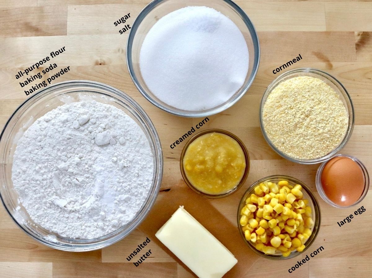 Cornbread-Cookies-Recipe Ingredients for corn cookies including corn kernels, creamed corn, butter, corn meal, flour and sugar - all is glass bowls on a cutting board.