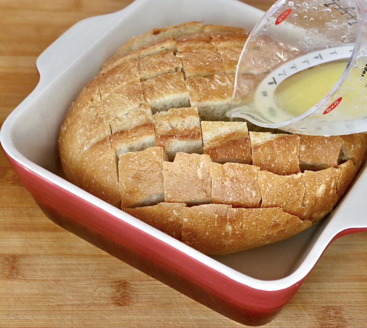 Pull-Apart French Toast Melted butter being poured from a measuring cup into the cracks of the bread.