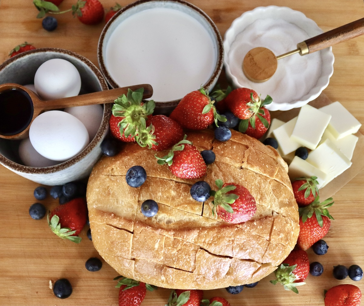 Pull-Apart French Toast Round loaf of French bread with slits cut into it, bowl of eggs, bowl of sugar, bowl of cream, several pats of butter, tablespoons of cinnamon and vanilla, with fresh berries - all for pull apart French toast.