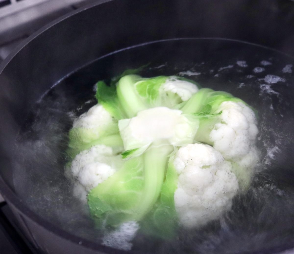 Whole-Cauliflower-One-Pan-Dinner-with-Tahini-Sauce Root end up, a whole cauliflower in boiling water.