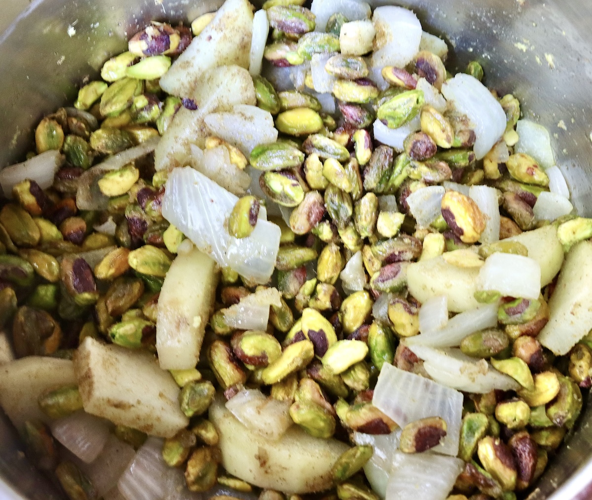 Pistachio-Soup-Recipe Top view of a pot with cooked onion, potato, and pistachios.